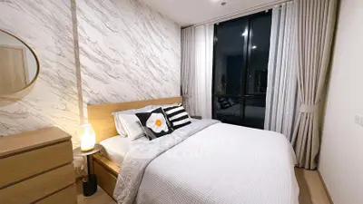 Modern bedroom with stylish decor and large window offering city views