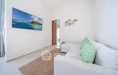 Bright living room with modern decor and wall-mounted TV, featuring a cozy white sofa and natural light.