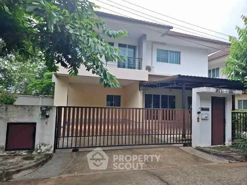 Charming two-story house with gated entrance and lush greenery, perfect for family living.