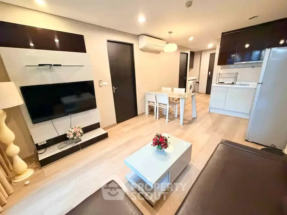 Modern living room with open kitchen, sleek furniture, and ambient lighting in a stylish apartment.