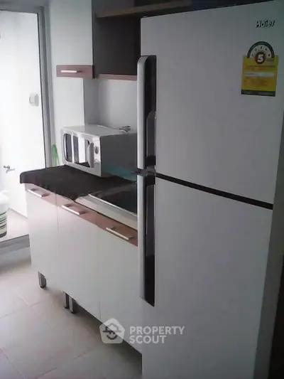 Modern kitchen with sleek refrigerator and microwave, perfect for contemporary living.