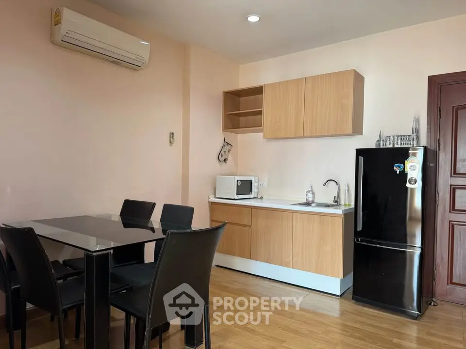 Modern kitchen with dining area, featuring sleek black chairs and compact appliances.