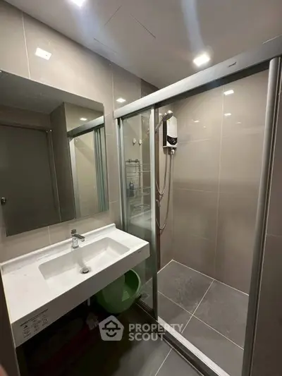 Modern bathroom with sleek shower enclosure and stylish sink in contemporary apartment.