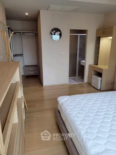 Modern bedroom with wooden furniture and ensuite bathroom in a stylish apartment.