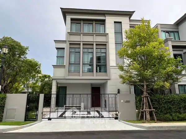Modern three-story residential building with gated entrance and lush greenery.