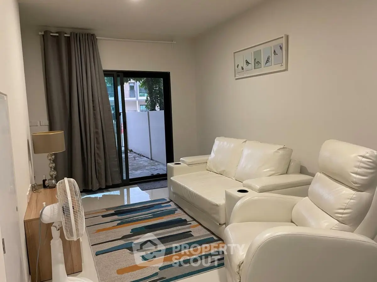 Modern living room with white leather furniture and sliding glass doors leading to a patio.