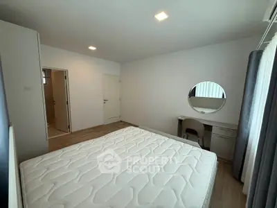 Spacious bedroom with modern decor and natural light, featuring a comfortable bed and stylish vanity area.