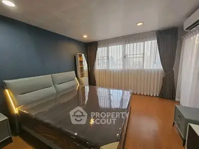 Spacious bedroom with modern decor and large windows offering ample natural light.