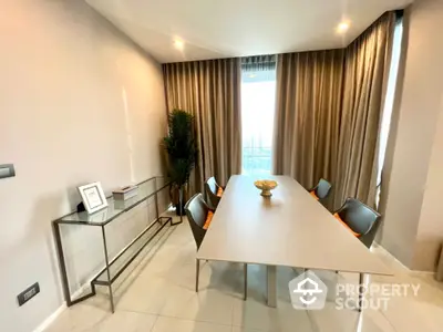 Elegant dining room with modern table and chairs, large window with curtains, and decorative plant.