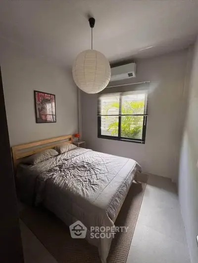 Cozy bedroom with modern decor and natural light, featuring a comfortable bed and stylish lighting.