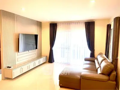 Spacious modern living room with sleek TV setup and large comfortable sofa.