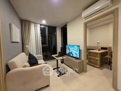 Modern living room with cozy sofa, TV, and study area in open layout apartment.