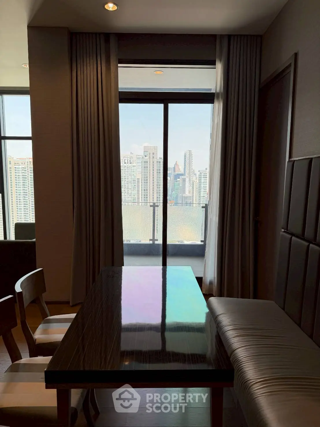 Modern dining area with city view through large window in high-rise apartment.