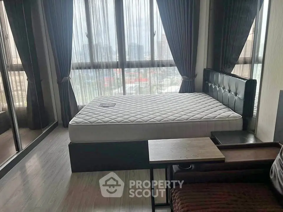 Spacious bedroom with large windows and modern furnishings in a high-rise apartment.