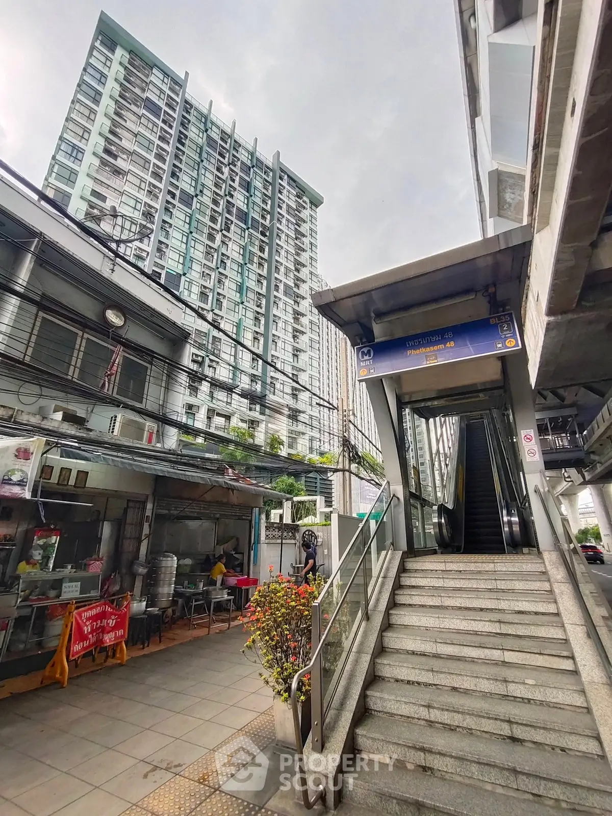 Modern urban building with adjacent escalator entrance in bustling city setting.