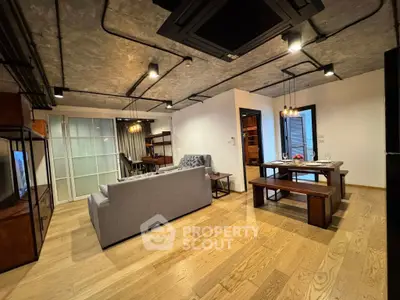 Modern industrial-style living room with open dining area and cozy seating.