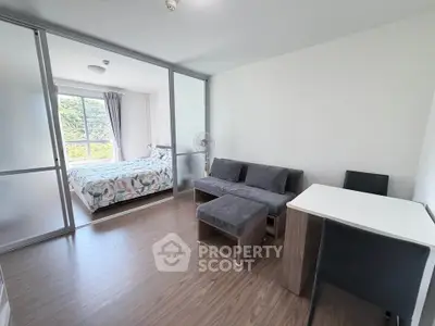 Modern apartment with cozy living room and bright bedroom, featuring sleek furniture and large windows.