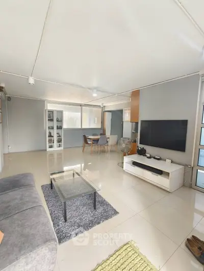 Spacious modern living room with sleek furniture and large TV, perfect for relaxation and entertainment.