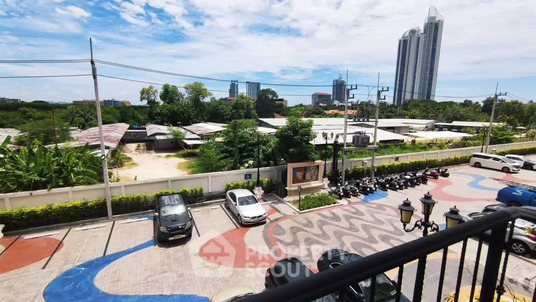 Scenic urban view from balcony overlooking parking area and city skyline.