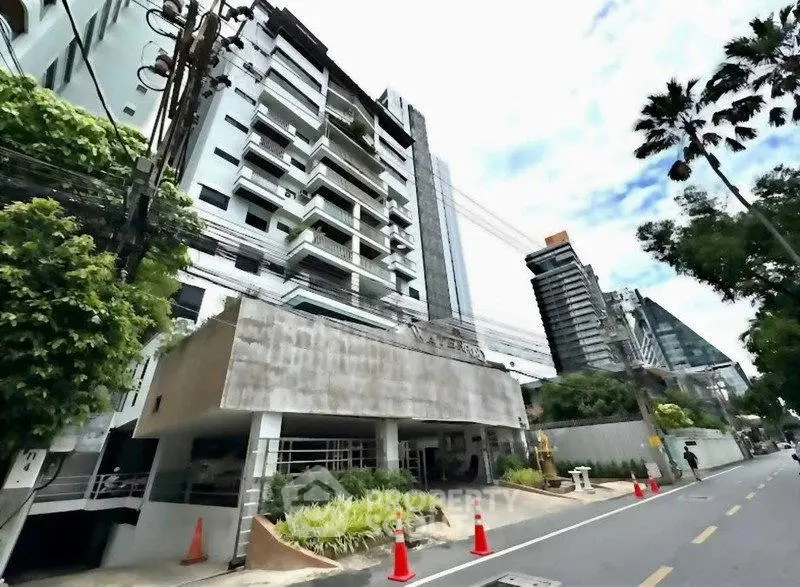 Modern urban building exterior with lush greenery and clear sky, showcasing contemporary architecture.