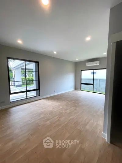 Spacious modern living room with large windows and wood flooring