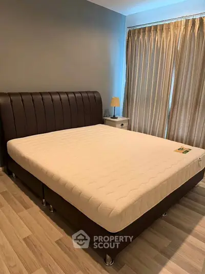 Spacious bedroom with elegant bed and natural light from large window.