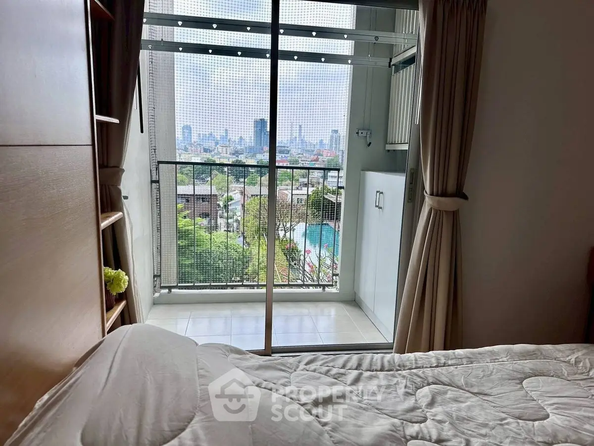 Cozy bedroom with balcony offering stunning city view and natural light.