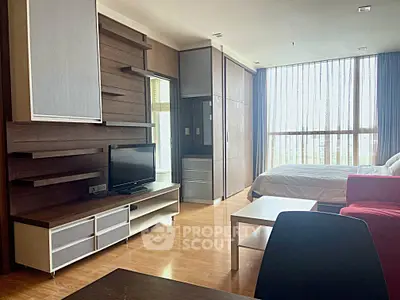 Modern studio apartment with wooden flooring, large windows, and stylish furniture.