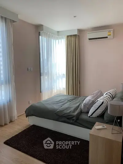 Modern bedroom with large windows, natural light, and stylish decor in a contemporary apartment.