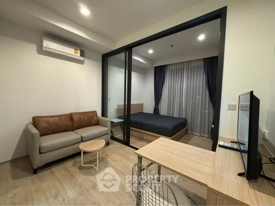 Modern studio apartment with glass partition, cozy living area, and stylish bedroom.