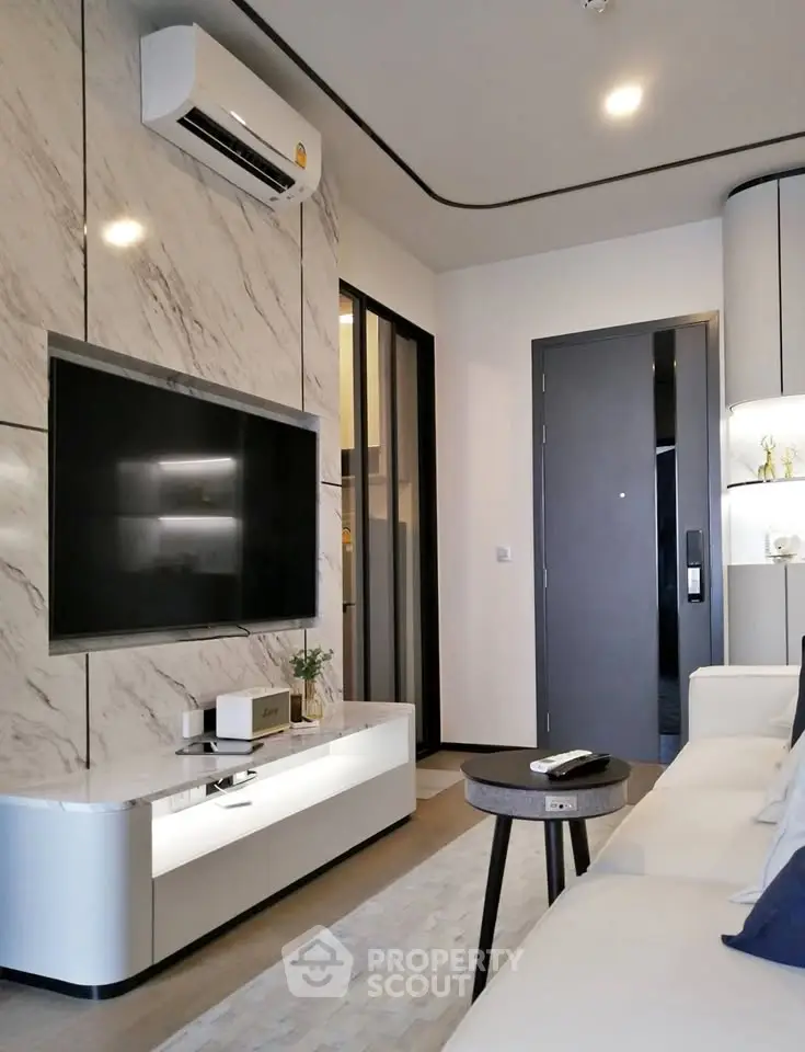 Modern living room with sleek marble wall, large TV, and stylish furniture in a contemporary apartment.
