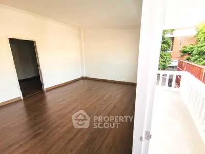 Spacious empty room with wooden flooring and balcony access, perfect for customization.