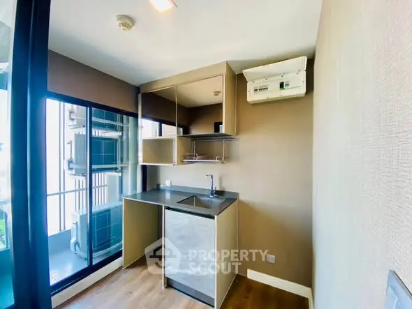 Modern compact kitchen with sleek design and balcony view, featuring built-in appliances and stylish cabinetry.