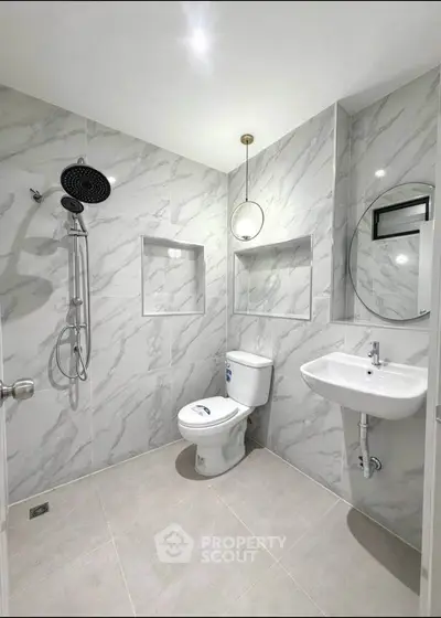 Modern bathroom with marble tiles, round mirror, and rainfall showerhead