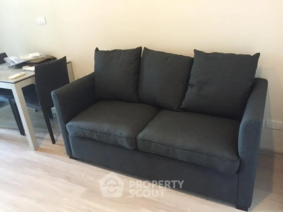 Modern living room with sleek gray sofa and dining table, perfect for cozy urban living.