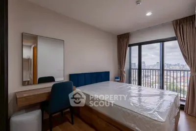 Modern bedroom with city view, featuring a stylish bed, desk, and large window for natural light.