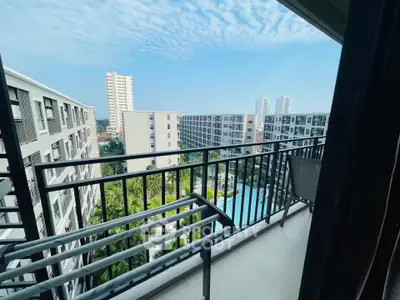 Stunning balcony view of modern apartment complex with pool and lush greenery.