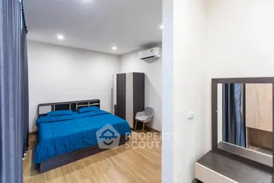 Modern bedroom with blue bedding, wooden flooring, and sleek furniture design.