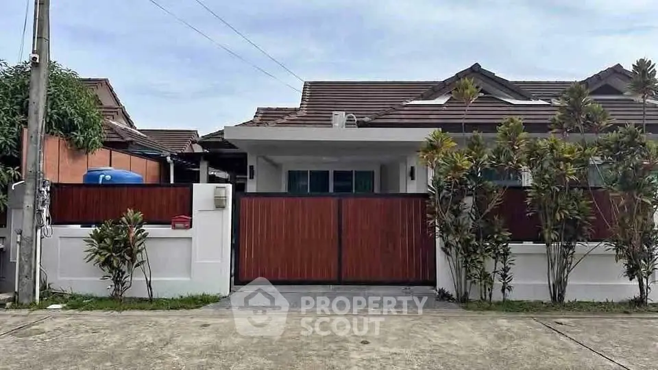 Charming single-story house with modern wooden gate and lush greenery in a serene neighborhood.