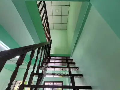 Stylish wooden staircase in modern home with mint green walls and ceiling tiles.
