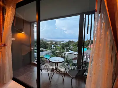 Stunning balcony view with cozy seating overlooking lush greenery and distant mountains.