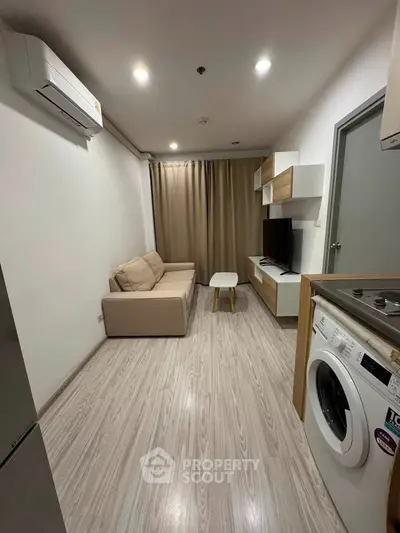 Modern living room with sleek design, featuring a cozy sofa, wall-mounted TV, and in-unit washing machine.