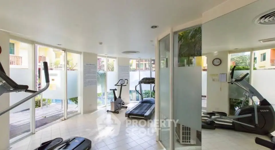 Bright and modern gym with large windows and exercise equipment in a residential building.
