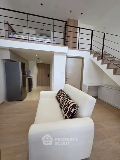 Modern loft apartment with stylish open layout and mezzanine bedroom, featuring sleek furniture and wooden flooring.