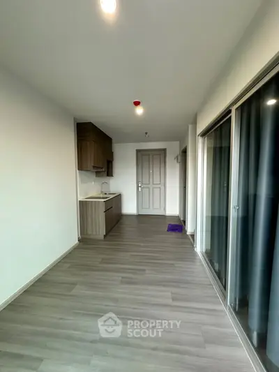 Modern apartment interior with sleek flooring and compact kitchen area, perfect for urban living.