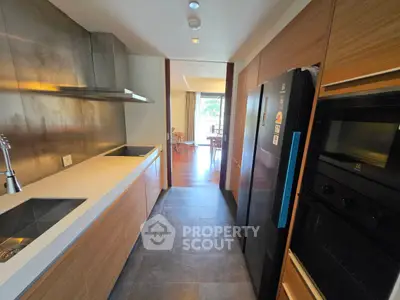 Modern kitchen with sleek appliances and open layout leading to dining area.
