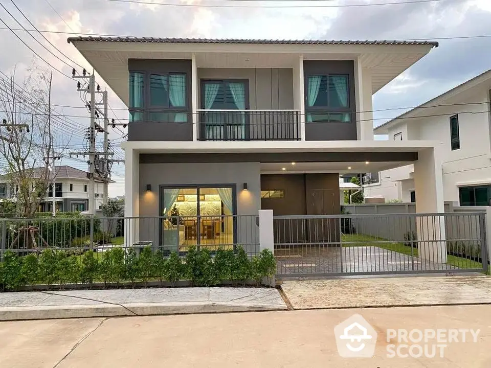 Modern two-story house with large windows and landscaped front yard in suburban neighborhood.