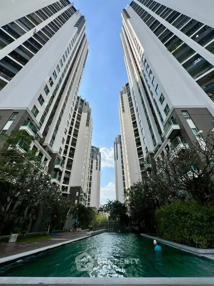Stunning view of modern high-rise residential buildings with a serene pool and lush greenery.