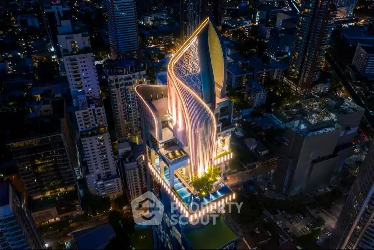 Stunning aerial view of a modern skyscraper with unique architectural design illuminated at night.