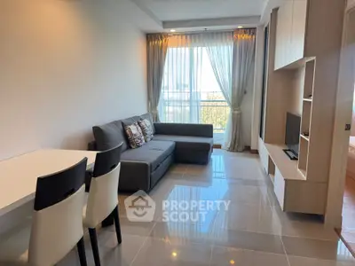 Modern living room with sleek furniture and large window offering natural light.
